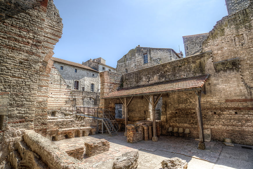 Ancient Roman ruins courtyard with stone walls and wooden shelter