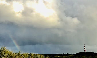 Lighthouse on Dunes with Rainbow and Dramatic Clouds