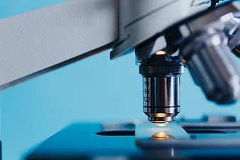 Close-up of microscope lens focusing on a slide in a laboratory