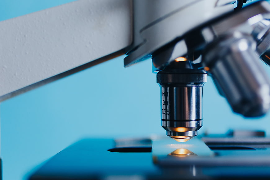 Close-up of microscope lens focusing on a slide in a laboratory