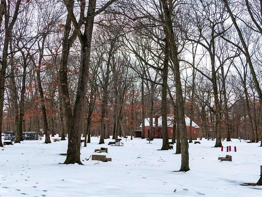 Snowy Winter Park with Bare Trees and Red Barn