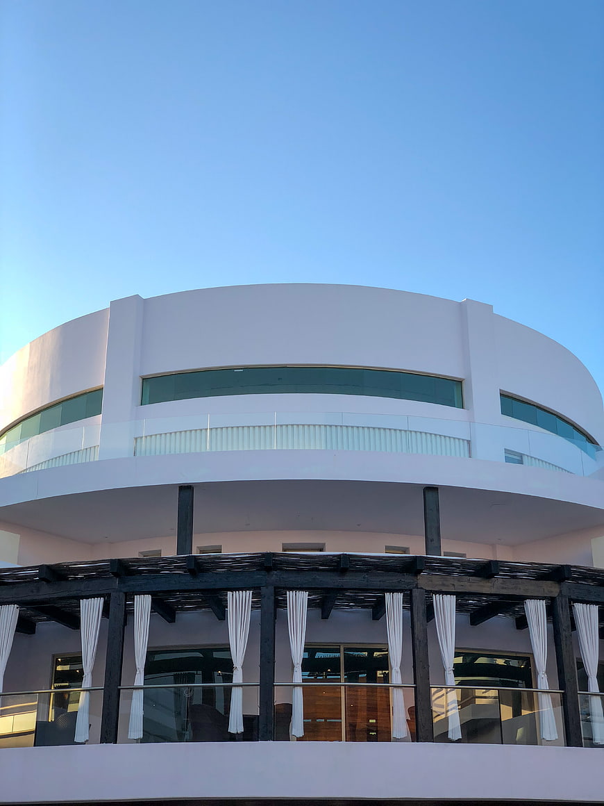 Modern white curved building with balcony and blue sky