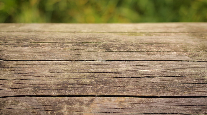 Weathered wooden table surface with blurred green background
