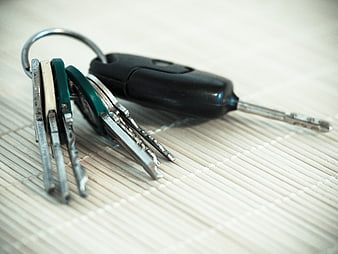 Close-up of metal keys and car remote on bamboo mat