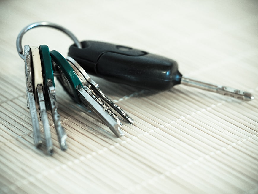 Close-up of metal keys and car remote on bamboo mat