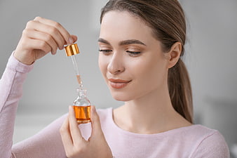 Woman holding skincare serum dropper bottle