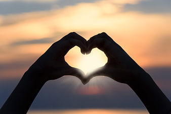 Silhouette of Hands Making Heart Shape Against Sunset Sky