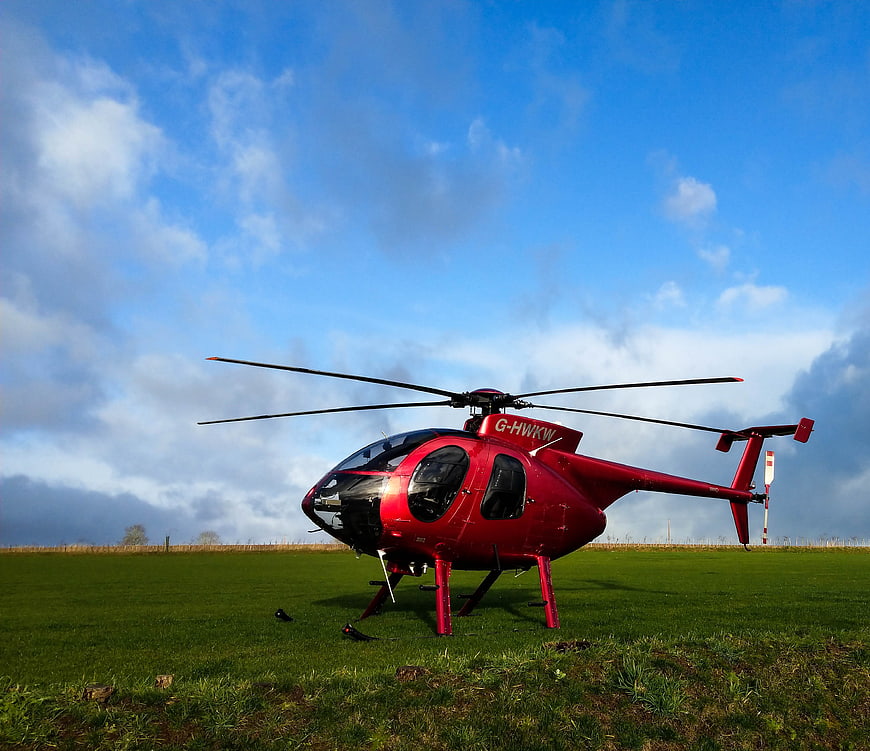 Red Helicopter on Green Field Under Blue Sky