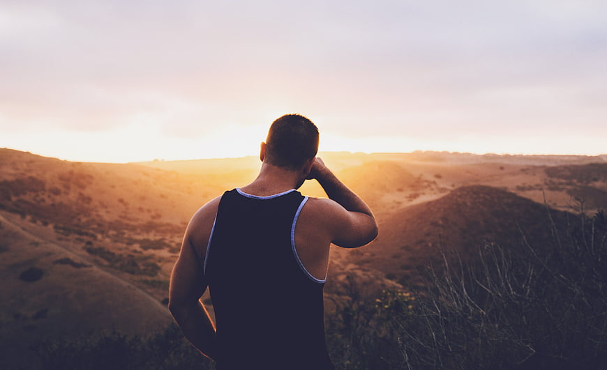 Man Looking at Sunset Over Rolling Hills