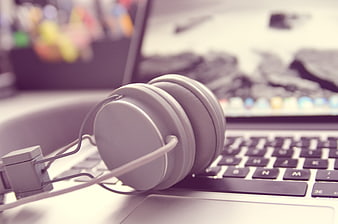 White headphones resting on laptop keyboard workspace