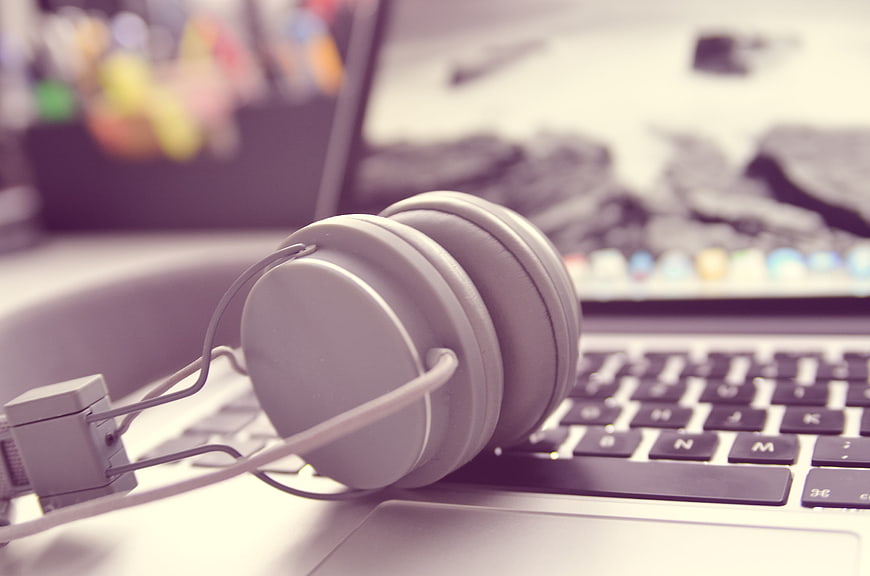 White headphones resting on laptop keyboard workspace