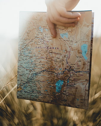 Hand pointing at California map in wheat field