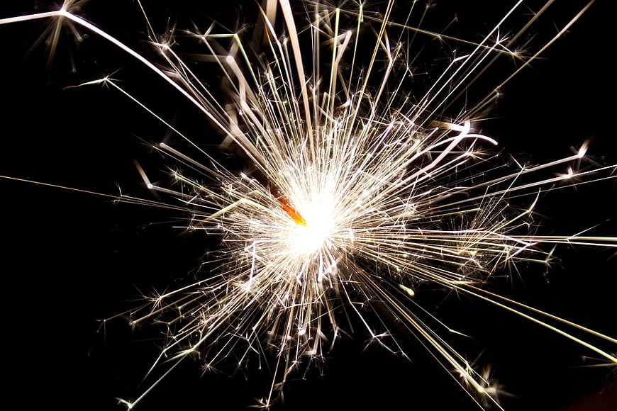 Bright Sparkler Bursting with Golden Sparks on Black Background