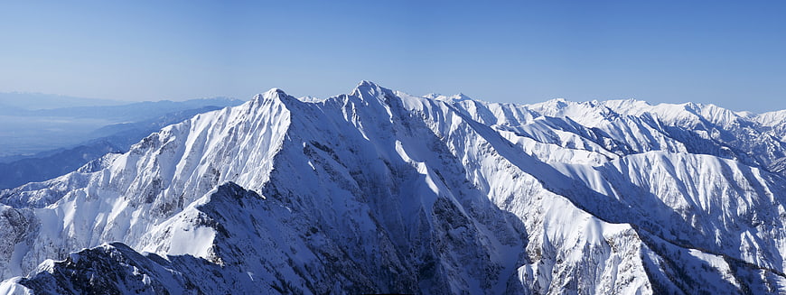 Snow-Covered Mountain Range Panorama Under Clear Blue Sky