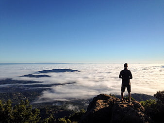 Man standing on rocky peak overlooking sea of clouds