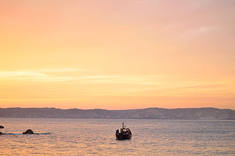 Fishing boat on calm sea during golden sunset