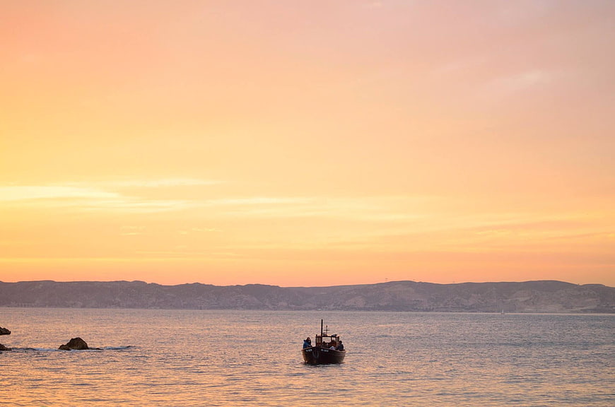 Fishing boat on calm sea during golden sunset