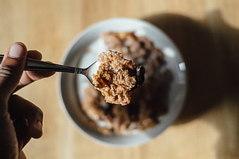 Close-up of spoonful of oatmeal with raisins over bowl