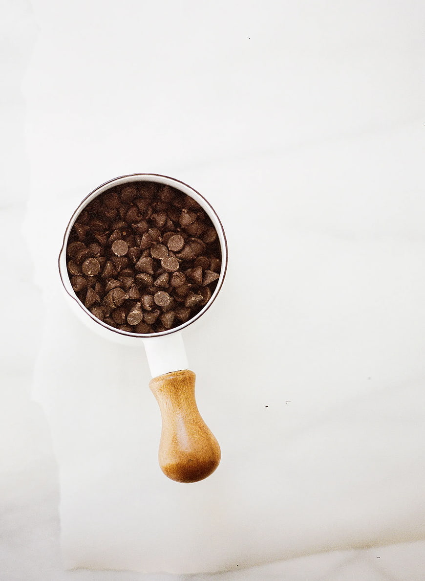 Top View of Chocolate Chips in White Mug with Wooden Handle