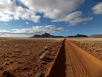 Red dirt road stretching through Namibian desert landscape
