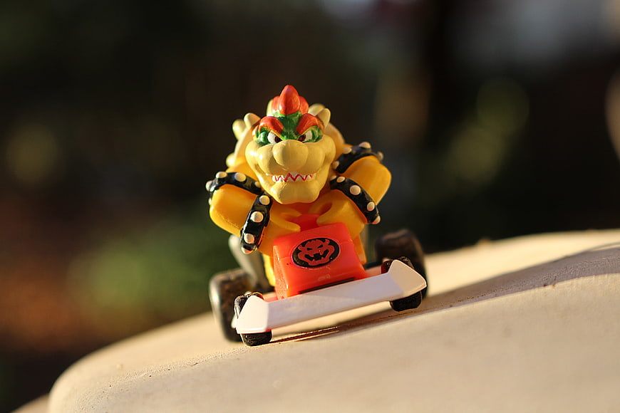 Bowser toy figure in a red kart on a sunny outdoor ledge