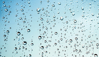 Water droplets on glass against blue sky background