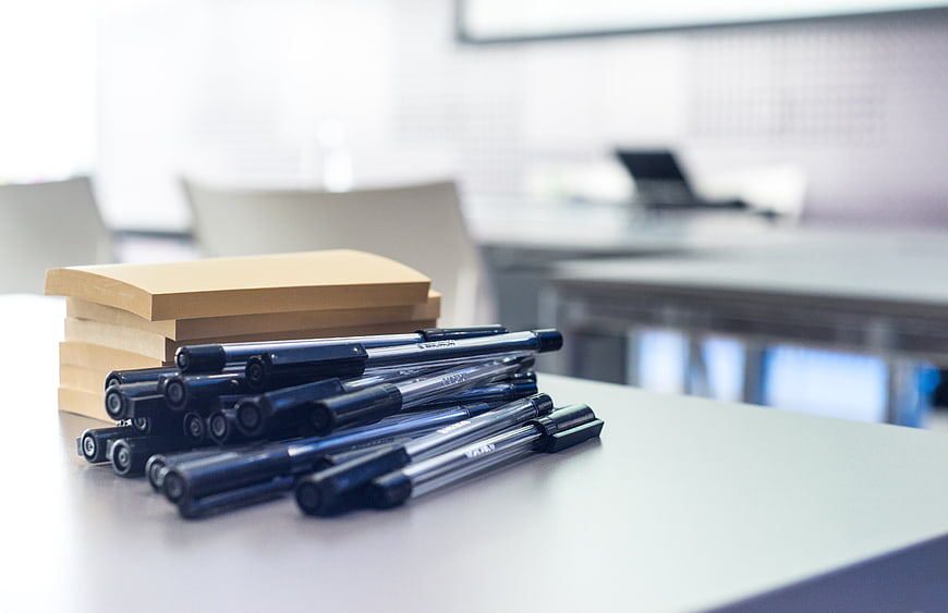 Stack of sticky notes and black pens on office desk