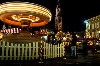 Nighttime Christmas Market With Spinning Carousel And Church Tower