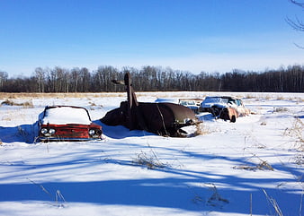 Abandoned vintage cars buried in snow field
