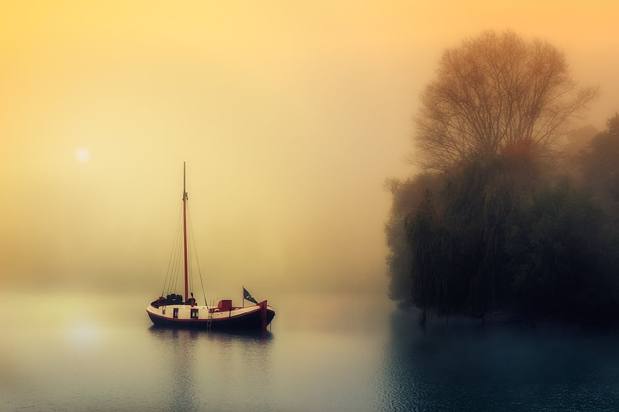 Sailboat on Misty Lake at Sunrise