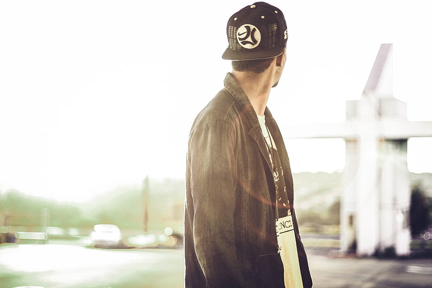 Man in Baseball Cap and Jacket Standing in Sunlight