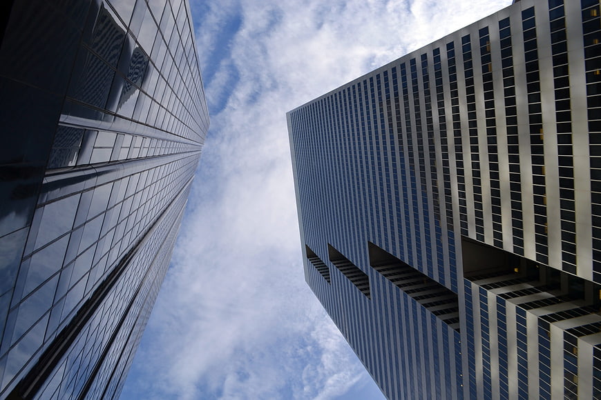 Low angle view of modern glass skyscrapers against blue sky