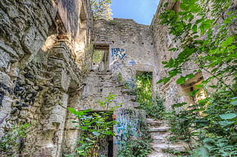 Abandoned stone ruins with graffiti and overgrown vegetation