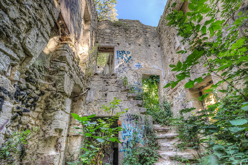 Abandoned stone ruins with graffiti and overgrown vegetation