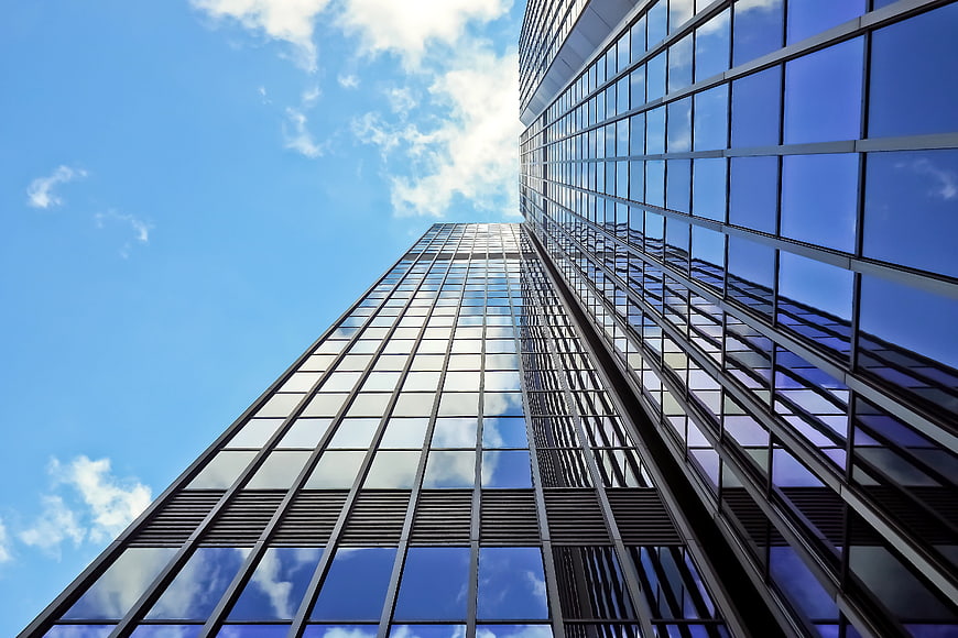 Low angle view of modern glass skyscraper against blue sky