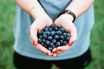 Woman holding fresh blueberries in cupped hands outdoors