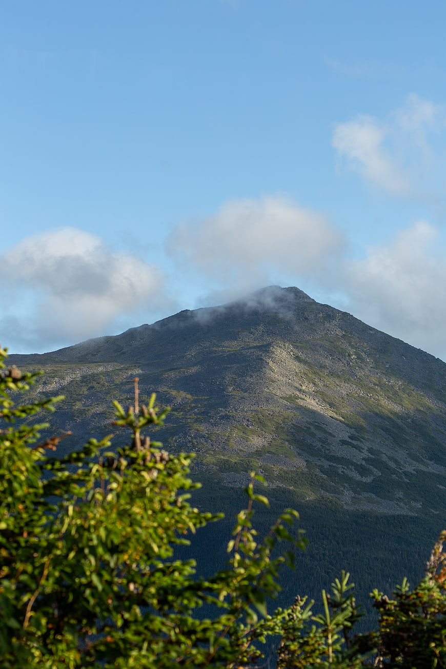 Majestic Mountain Peak with Clouds and Foreground Trees