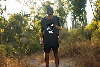 Young man in oversized t-shirt walking on forest path