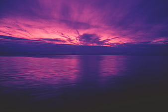Vibrant purple and pink sunset over calm ocean water