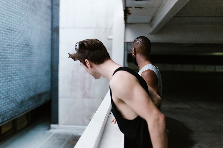 Two men leaning on railing in urban parking garage