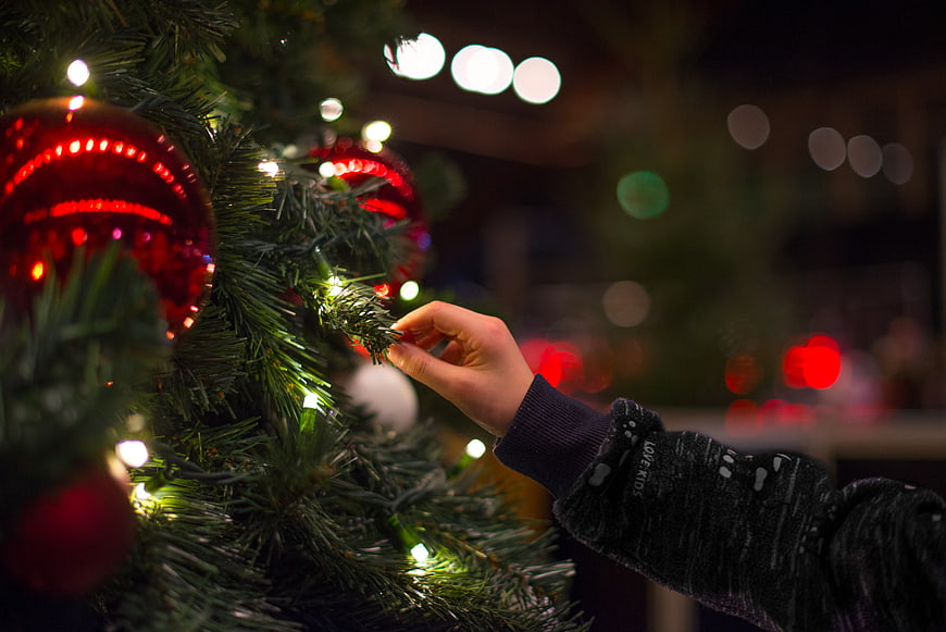 Child's Hand Touching Christmas Tree Lights and Ornaments