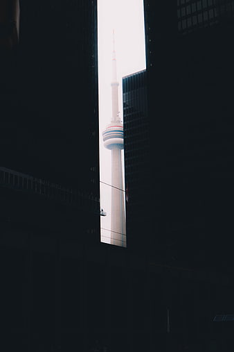 CN Tower framed between dark skyscrapers in Toronto