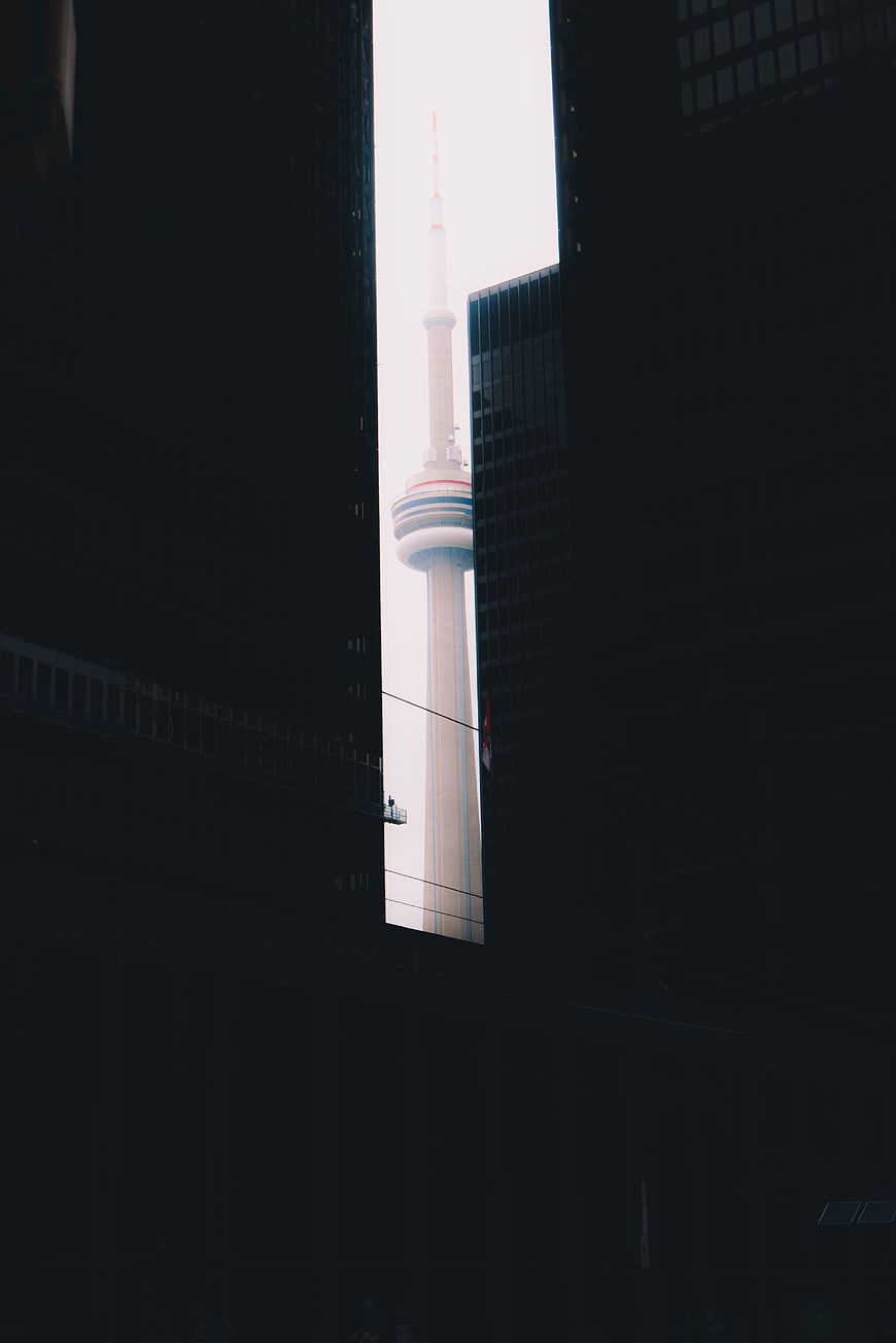 CN Tower framed between dark skyscrapers in Toronto