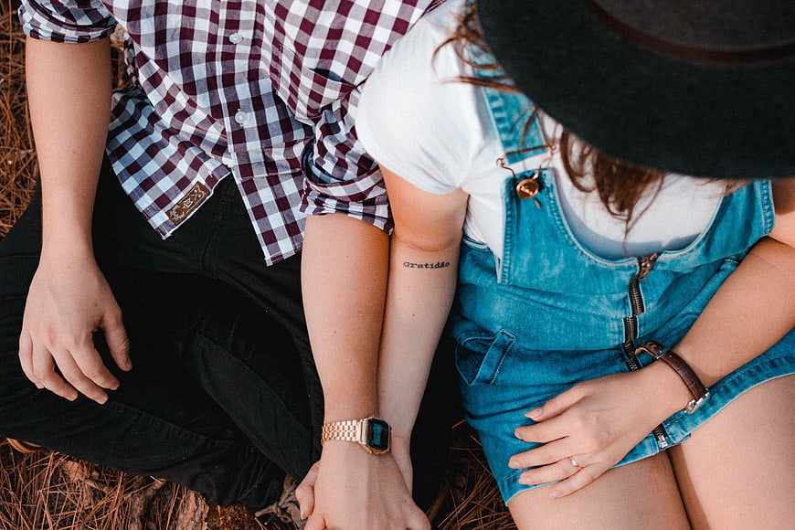 Couple holding hands with gratitude tattoo in nature