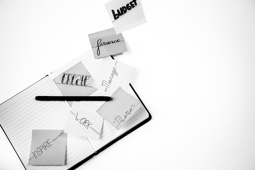 Black and white notebook with sticky notes and pen