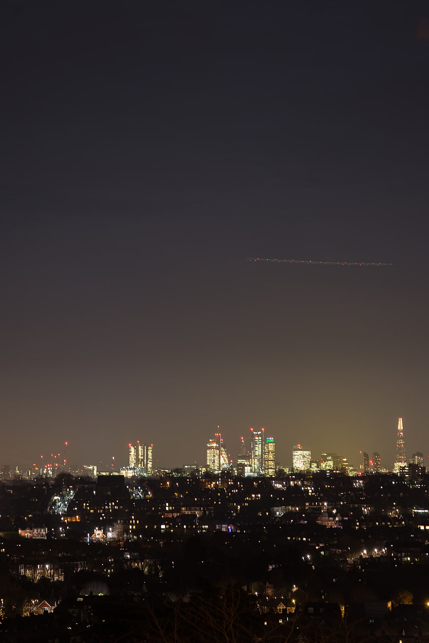 London Skyline at Night with Airplane Trail