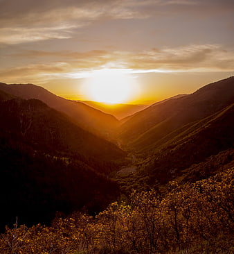 Golden sunset over mountain valley with winding road