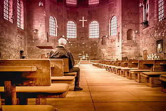 Senior man praying alone in rustic brick church interior