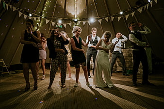 Wedding guests dancing in a decorated marquee tent at night