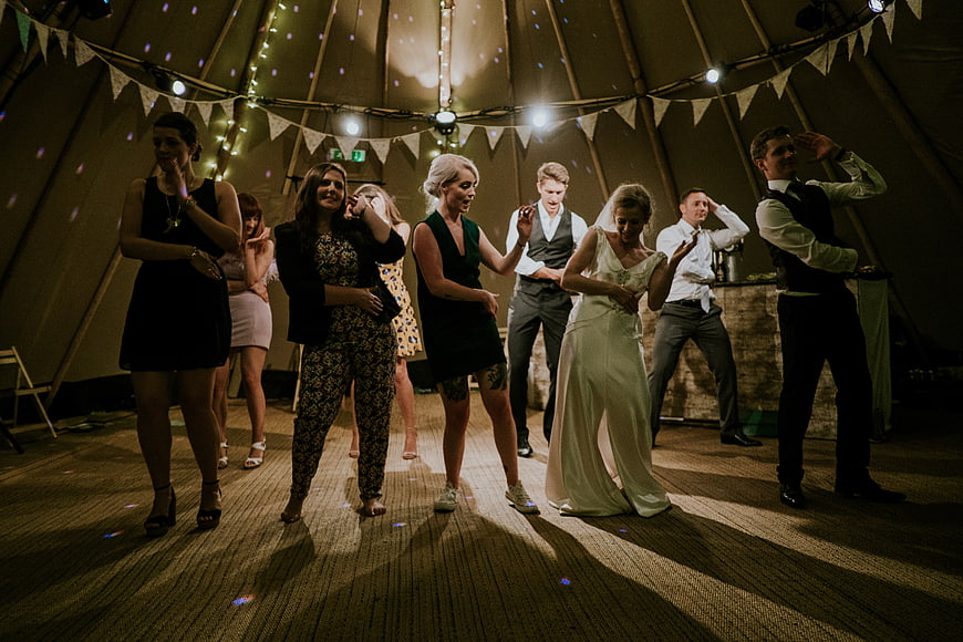 Wedding guests dancing in a decorated marquee tent at night
